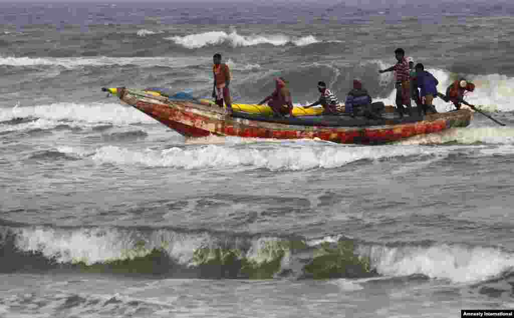 Para nelayan India yang berada di laut kembali ke pantai setelah pemerintah setempat mengumumkan peringatan bahaya topan di kota Gopalpur, negara bagian Orissa, India timur.