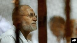 FILE - Leader of Egypt's Muslim Brotherhood Mohamed Badie sits inside a defendant's cage during his trial in Cairo, Egypt, April 30, 2014.