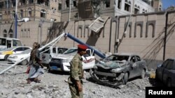 Anggota kelompok militan Houthi berjalan melewati mobil-mobil yang hancur di luar Kompleks Presidensial pasca hantaman serangan udara di Sanaa, Yaman, 7 Mei 2018. (Foto: dok).