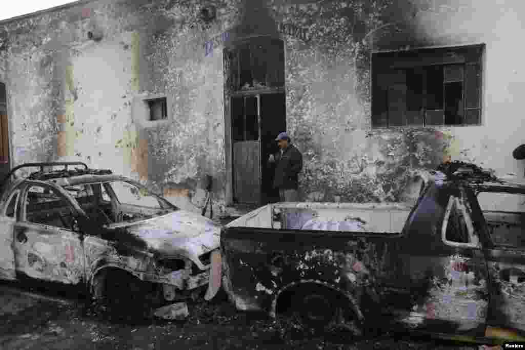 A man stands next to the wreckage of burnt vehicles outside the Guadalupe Victoria town hall in the Mexican state of Puebla. Residents burned the town hall, patrol vehicles and two buildings belonging to Mayor Felipe Cortes, to demand more security in the area after a local shopkeeper was recently killed by unknown assailants during a robbery, according to local media.