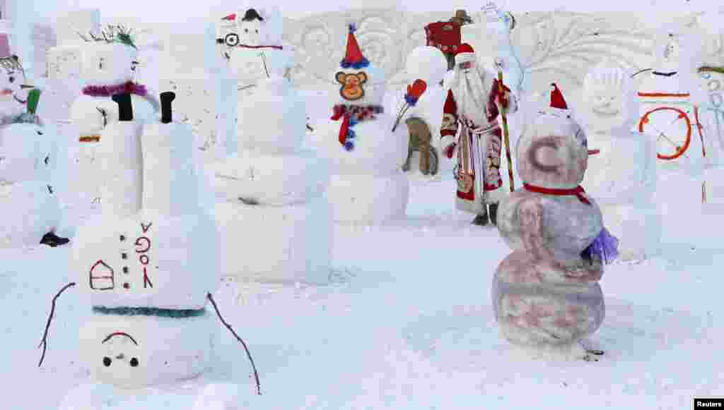 A man dressed as Ded Moroz (Old man Frost or Grandfather Frost), the Russian equivalent of Santa Claus, walks while selecting the best snowman during the festive pre-holiday competition 'Parade of Snowmen' at the Royev Ruchey Flora and Fauna Park on the suburbs of the Siberian city of Krasnoyarsk, Russia.