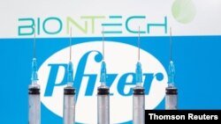 FILE - Syringes are seen in front of displayed Biontech and Pfizer logos in this illustration taken November 10, 2020.