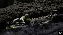 Socorristas trabajan en un vehículo que cayó en un socavón hace días, el jueves 29 de septiembre de 2022, en Villa Nueva, Guatemala. 