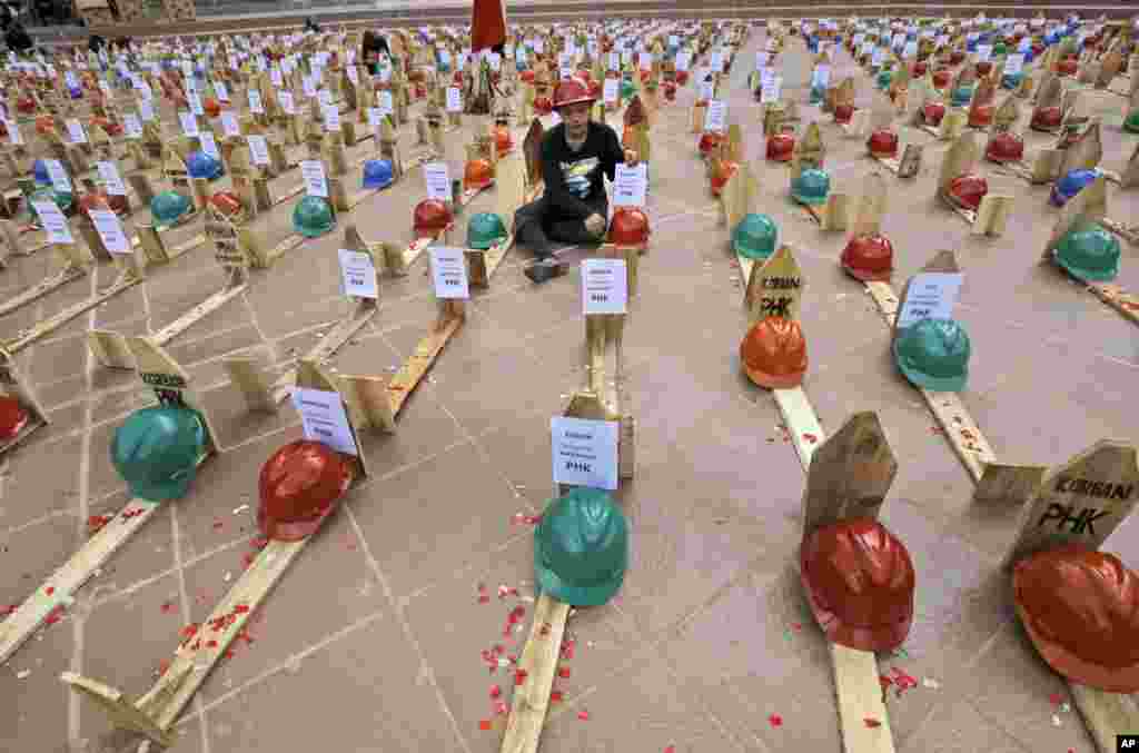 An activist of National Solidarity of Mine Workers sits among mock graves of miners during a protest against the government's plan to ban raw mineral exports that will take effect this month, in Jakarta, Indonesia.
