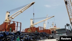 Des ouvriers déchargent des tuyaux sur un chantier de construction de la raffinerie de pétrole Dangote dans le quartier d'Ibeju Lekki, dans la banlieue de Lagos, au Nigeria, le 7 août 2019.