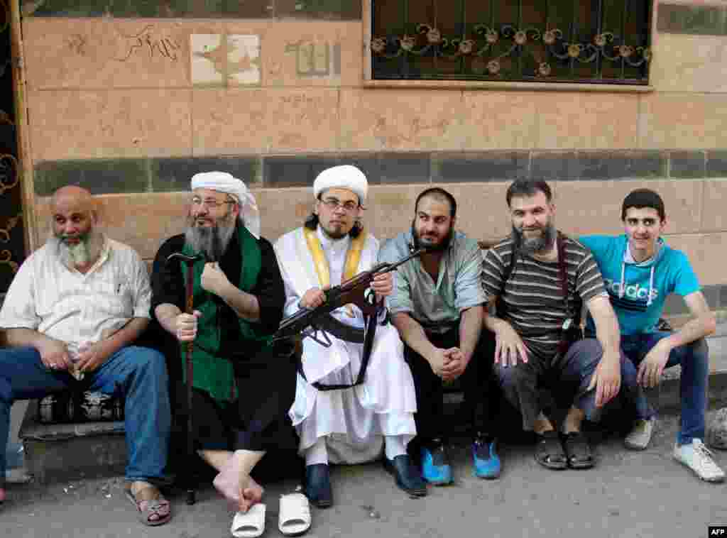 Sheikh Abu Rateb (2nd-R), the head of the Right Brigade, poses with other protesters during a demonstration against the Syrian regime after the Eid al-Fitr prayer in Homs, August 8, 2013.