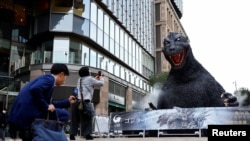 Personas toman fotografías de una estatua de Godzilla promocional de la película 'Godzilla Minus One' en Tokio, Japón, el 11 de marzo de 2024, después de que ganara el Oscar a los mejores efectos visuales durante la entrega de lo 96a edición de los Oscar.