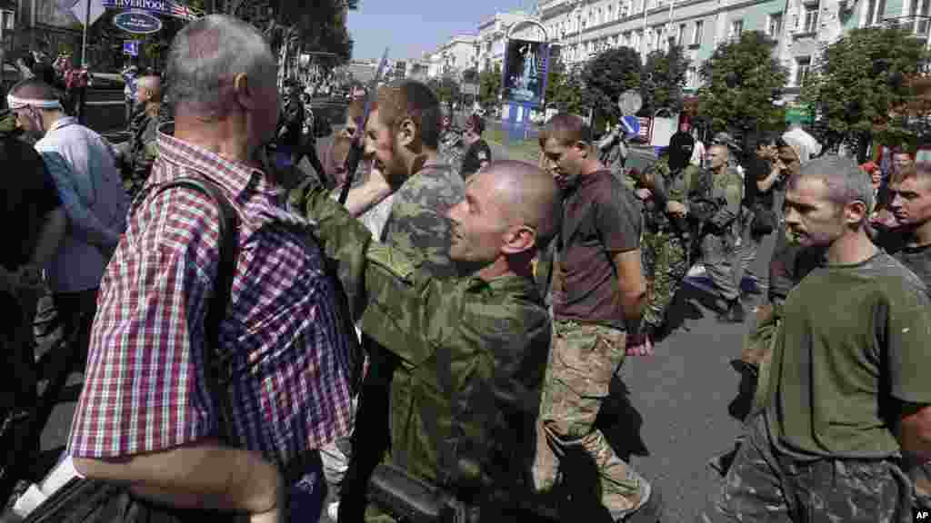 Pro-Russian rebel tries to stop a man who slaps a captured Ukrainian army prisoner they are escorting on central square in Donetsk, eastern Ukraine, Aug. 24, 2014.