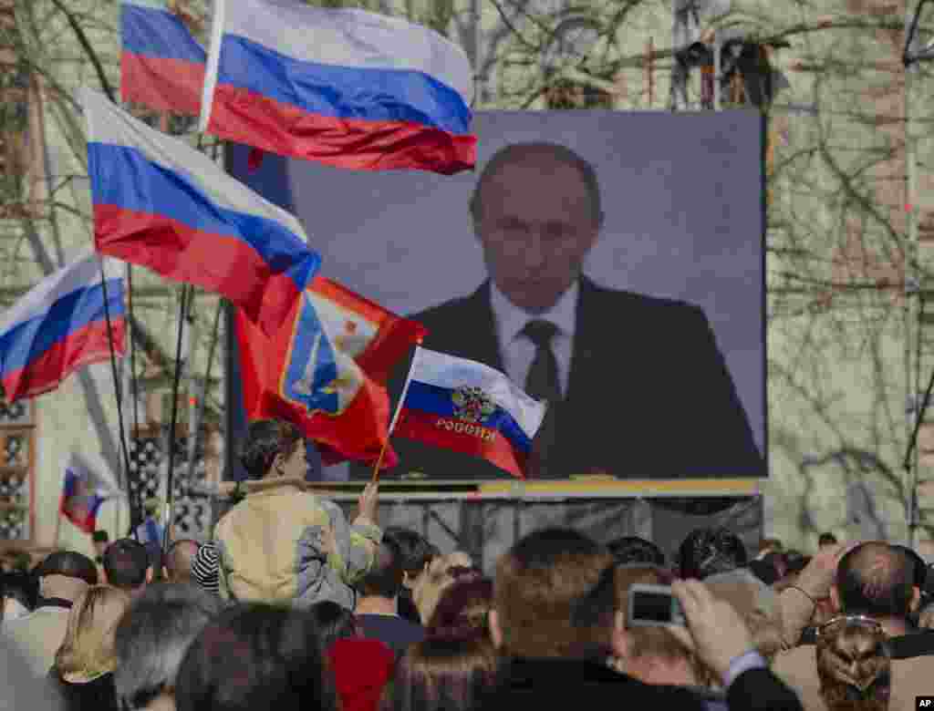 Pro-Russian people watch a live broadcast of Russian President Vladimir Putin's speech on Crimea in Sevastopol, Crimea, March 18, 2014.
