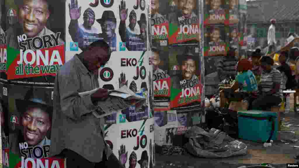 A man reads a newspaper in front of electoral campaign posters in Lagos, Nigeria, March 30, 2015.