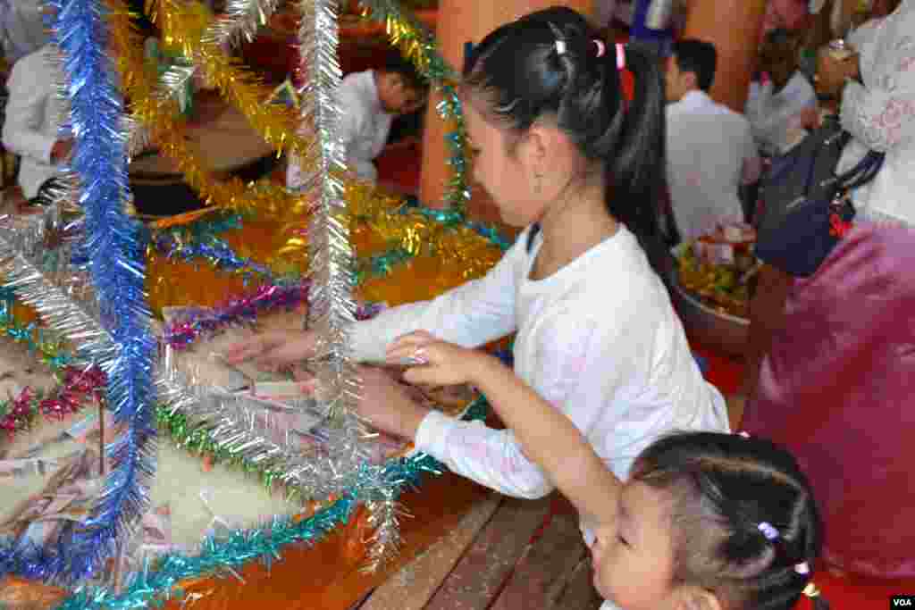 ក្មេងៗចូលរួមជាបច្ច័យនៅថ្ងៃបុណ្យភ្ជុំបិណ្ឌ ក្នុងវត្តមួយនៅជាយក្រុងភ្នំពេញ កាលពីថ្ងៃអង្គារ ទី០៩ ខែតុលា ឆ្នាំ២០១៨។ (ណឹម សុភ័ក្រ្តបញ្ញា/VOA)