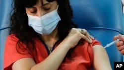 Dr. Estefania Zevrnja gets a shot of Russia's Sputnik V vaccine for COVID-19 at Dr. Pedro Fiorito Hospital in Avellaneda, Argentina, Tuesday, Dec. 29, 2020. (AP Photo/Natacha Pisarenko)
