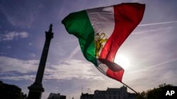 FILE - People wave a pre-Islamic revolution Iran's flag as they take part in a protest against Iranian authorities, in London, Oct. 29, 2022.