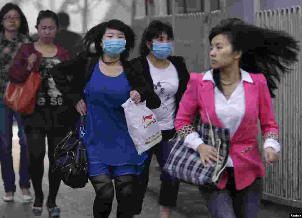 Women wearing face masks run to cross a street in Beijing, May 6, 2013. The United States Embassy monitor on air quality in China classified the quality of air in Beijing as "hazardous."