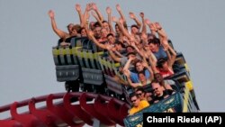 People ride a roller coaster at Worlds of Fun amusement park Saturday, June 2013, in Kansas City, Missouri. (AP Photo/Charlie Riedel)