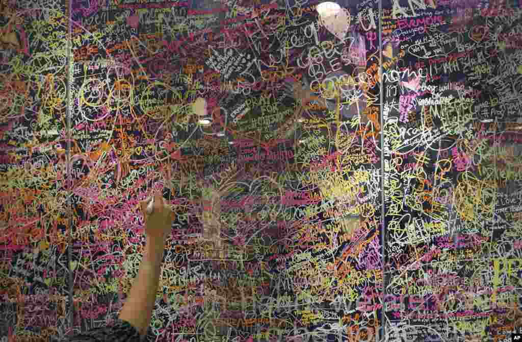 A woman writes a message for passengers aboard a missing Malaysia Airlines plane, on a glass wall at a shopping mall in Kuala Lumpur, Malaysia.