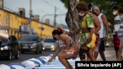Moradores colocam rosas em colchões simbolizando as vítimas da COVID-19, durante um protesto contra a gestão do governo da pandemia, organizado pela ONG Rio de Paz, em frente ao hospital Ronaldo Gazolla no Rio de Janeiro, Brasil, a 24 de Março de 2021