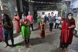 Indians, wearing face mask and maintaining physical distance, participate in religious rituals during Navratri or nine nights festival celebrations in Ahmedabad, Oct. 21, 2020.