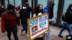 A protester holding a sign reading 'Stop Killing Us' navigates along Chicago's Loop during a peaceful protest, April 14, 2021, ahead of the video release of the fatal police shooting of 13-year-old Adam Toledo. 