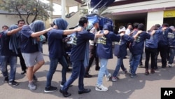 FILE - Police officers escort men arrested in a raid on a gay sauna at North Jakarta police headquarters in Jakarta, Indonesia, May 22, 2017. Indonesian police detained dozens of men Sunday in a similar raid, another sign of growing hostility to homosexuality in the world's most populous Muslim nation.