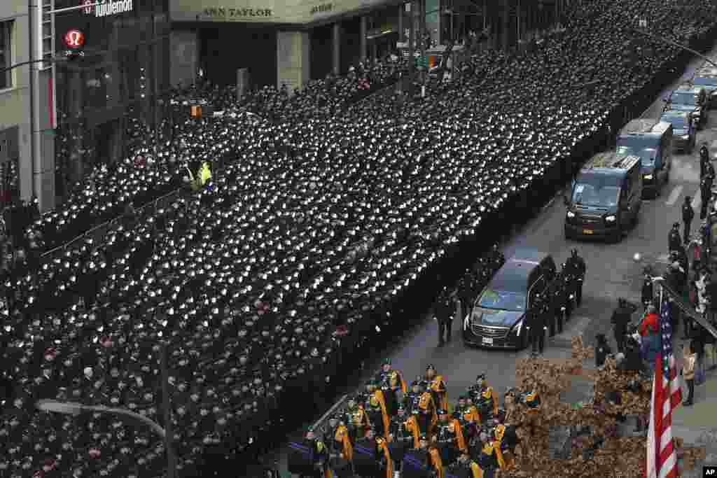 New York Police salute as a hearse carrying the casket of NYPD Officer Wilbert Mora is escorted down Fifth Avenue after his funeral service at St. Patrick's Cathedral in New York. Mora was shot along with Officer Jason Rivera on Jan. 22 while responding to a call about a domestic argument in an apartment.