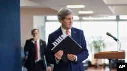 FILE - U.S. Secretary of State John Kerry picks up his notebook after answering questions from members of the media before his departure from Ben Gurion International Airport in Tel Aviv.