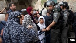 Palestinian Muslim worshippers wait as Israeli border guards have their documents and belongings checked at the entrance of al-Aqsa mosque compound in Jerusalem's Old city, April 20, 2014.