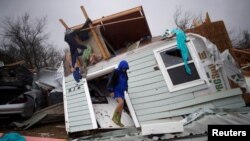 Barbara Koster berdiri di depan pintu depan rumahnya sembari melihat kerusakan pada rumahnya akibat badai tropis Harvey di Rockport, Texas, 26 August 2017.