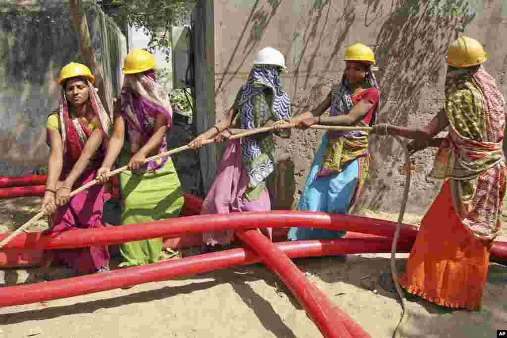 Women laborers work to lay a cable for an electricity company on International Women's Day in Ahmadabad, India, March 8, 2013. 