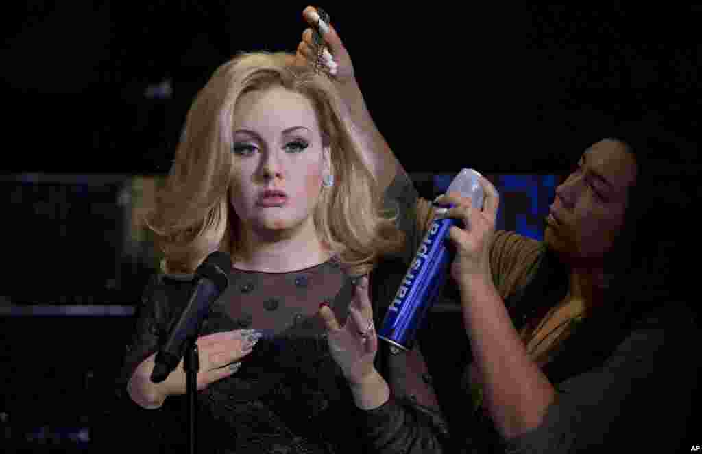 Stylist Gemma Sim, right, adjusts the hair of the wax figure of British singer Adele, as it is revealed at Madame Tussauds in central London.