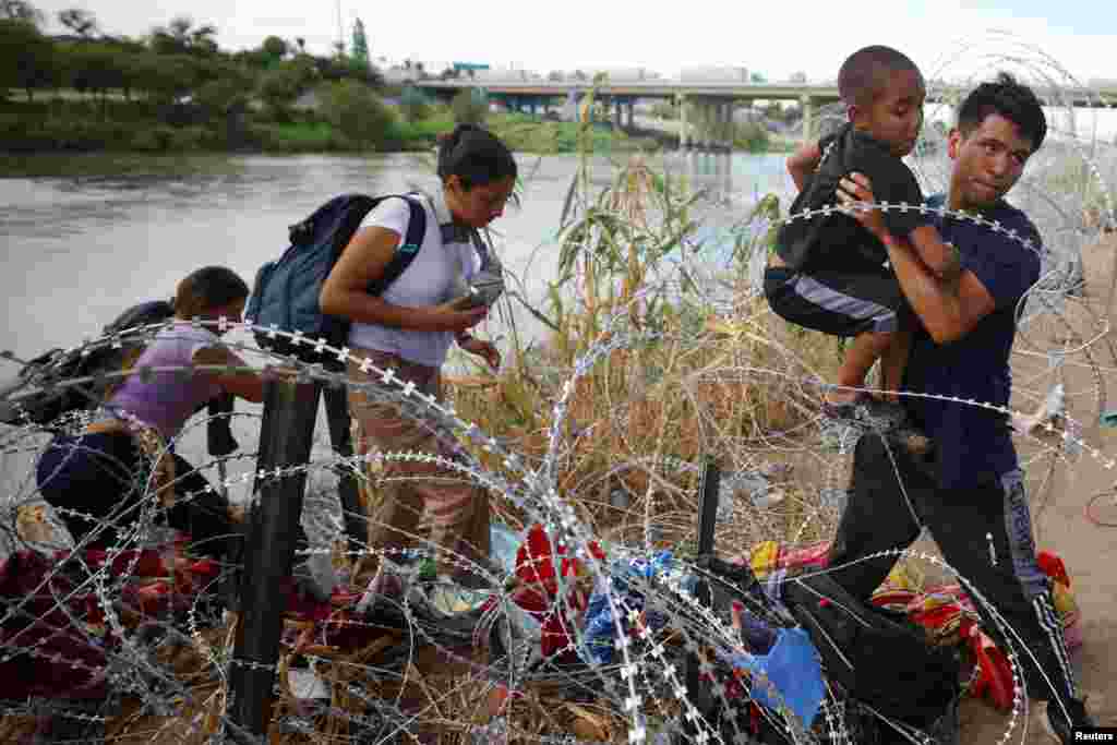 Migrants from Venezuela make their way through the razor wire after crossing the Rio Grande into the United States in Eagle Pass, Texas, Sept. 26, 2023. 