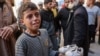 Um rapaz chora enquanto segura nos sapatos de uma criança que morreu atingida por estilhaços na sequência de um ataque israelita na cidade de Gaza, no hospital árabe Al-Ahli, a 5 de dezembro de 2024