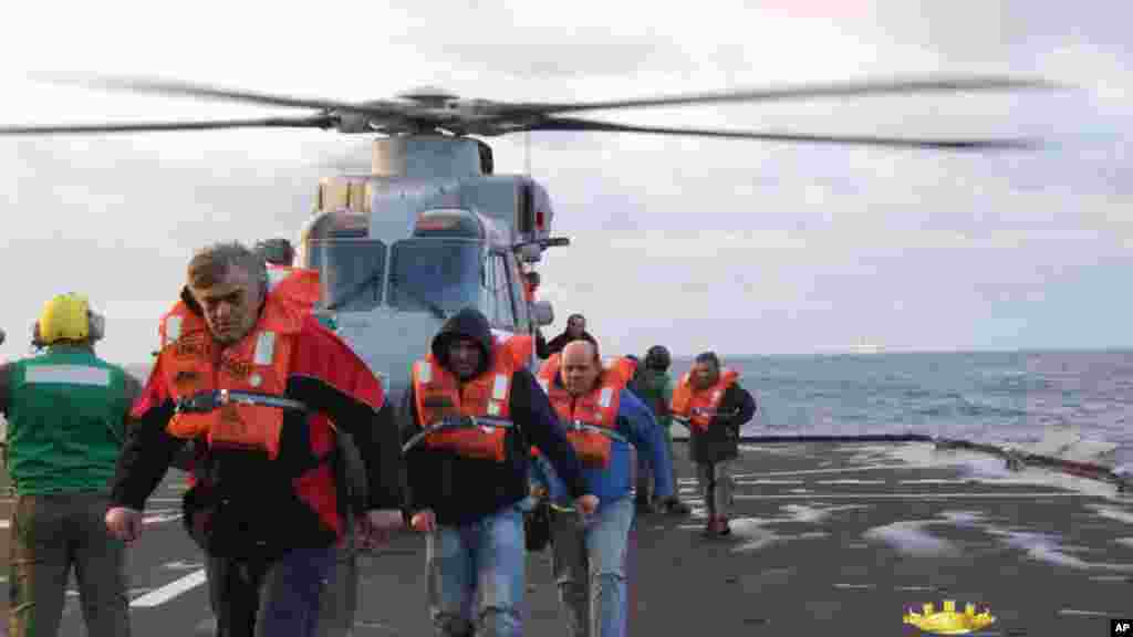 In this image released by the Italian Navy, passengers and crew of the Italian-flagged Norman Atlantic, that caught fire in the Adriatic Sea, are rescued from the Italian Navy ship San Giorgio, Dec. 29, 2014.