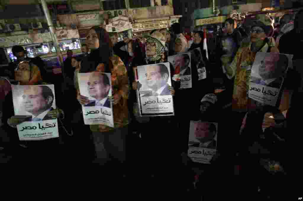 Supporters of former army chief Abdel-Fattah el-Sissi hold posters of him with Arabic writing that reads "Long Live Egypt" while watching his first televised interview on a big screen, Cairo, May 5, 2014.