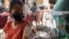 Seorang perempuan menerima satu dosis vaksin AstraZeneca COVID-19 saat program vaksinasi massal untuk Kawasan Wisata Hijau di Sanur, Bali, 23 Maret 2021. (Foto: REUTERS/Nyimas Laula)