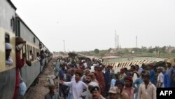 Railway workers repair the tracks next to damaged carriages a day after the derailment of a passenger train in Nawabshah on Aug. 7, 2023.