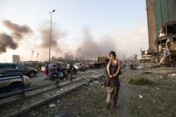 Personas evacúan heridos luego de una masiva explosión en el centro de Beirut, que destruyó la mayor parte del puerto, dañó edificios, hizo volar balcones, puertas y ventanas y causó una enorme nube de humo sobre la capital libanesa. Agosto 4, 2020.