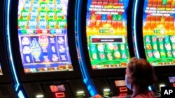 FILE - A woman plays a slot machine at the Golden Nugget casino in Atlantic City, New Jersey, July 2, 2020.
