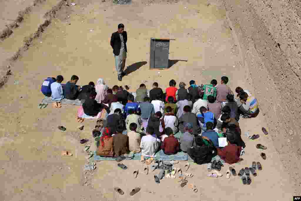 Anak-anak SD di kota Ghazni, Afghanistan belajar di lapangan terbuka.