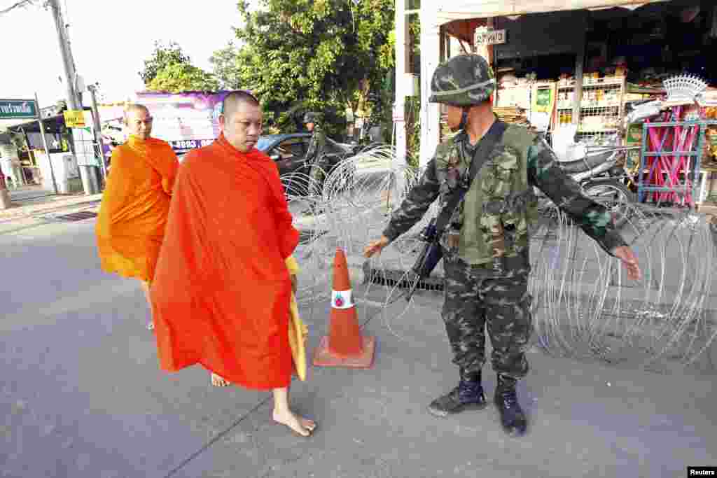 Tu sĩ Phật giáo đi ngang qua một chốt kiểm soát gần doanh trại của phe 'áo đỏ' ủng hộ chính phủ trong tỉnh Nakhon Pathom ở ngoại ô Bangkok, Thái Lan, ngày 22/5/2014.