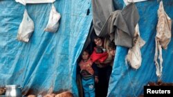 FILE - Displaced Syrian children look out from their tents at Kelbit refugee camp, near the Syrian-Turkish border, in Idlib province, Syria, Jan. 17, 2018. 