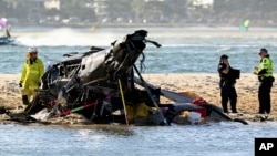Petugas darurat memeriksa helikopter di tempat kejadian tabrakan dekat Seaworld, di Gold Coast, Australia, Senin, 2 Januari 2023. (Foto: via AP)