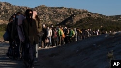 Migrantes chinos esperan ser procesados tras cruzar la frontera con México, el miércoles 8 de mayo de 2024, cerca de Jacumba Hot Springs, California.