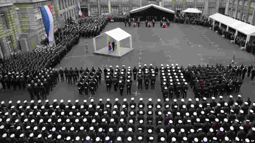 French President Francois Hollande delivers his speech, at left, during a ceremony to pay tribute to the three police officers killed in the attacks, in Paris, France, Jan. 13, 2015.