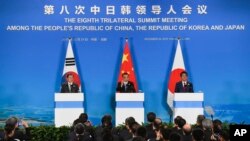 China's Premier Li Keqiang, center, speaks, as South Korea's President Moon Jae-in, left, and Japanese Prime Minister Shinzo Abe, right, listen to him during a joint press conference after their trilateral leaders' meeting in China.