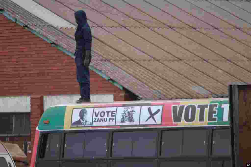 A man observes from on top of a campaign bus for President Robert Mugabe near a polling station during Presidential and parliamentary elections in the Southern African Nation in Harare.