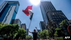 Un manifestante ondea una bandera de México durante una protesta contra el presidente Andrés Manuel López Obrador, en medio de pandemia del coronavirus.