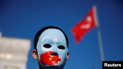 Seorang lelaki etnis Uighur mengenakan topeng saat protes terhadap China di Istanbul, Turki, 14 Desember 2019. (Foto: Reuters)