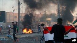Anti-government demonstrators set fires and block a street during a violent protest in Baghdad, Iraq, Oct. 3, 2019.