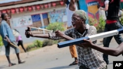 A demonstrator uses a slingshot during clashes with security forces in the Cibitoke district of the capital Bujumbura, Burundi Friday, May 29, 2015.